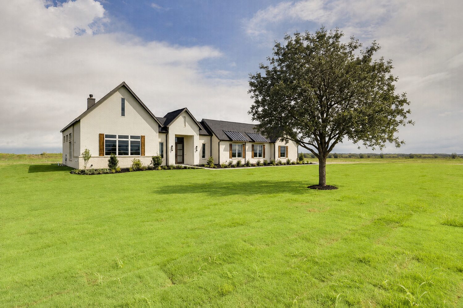 A white brick custom home by Killian Custom Homes, set on open Texas acreage beside a mature shade tree